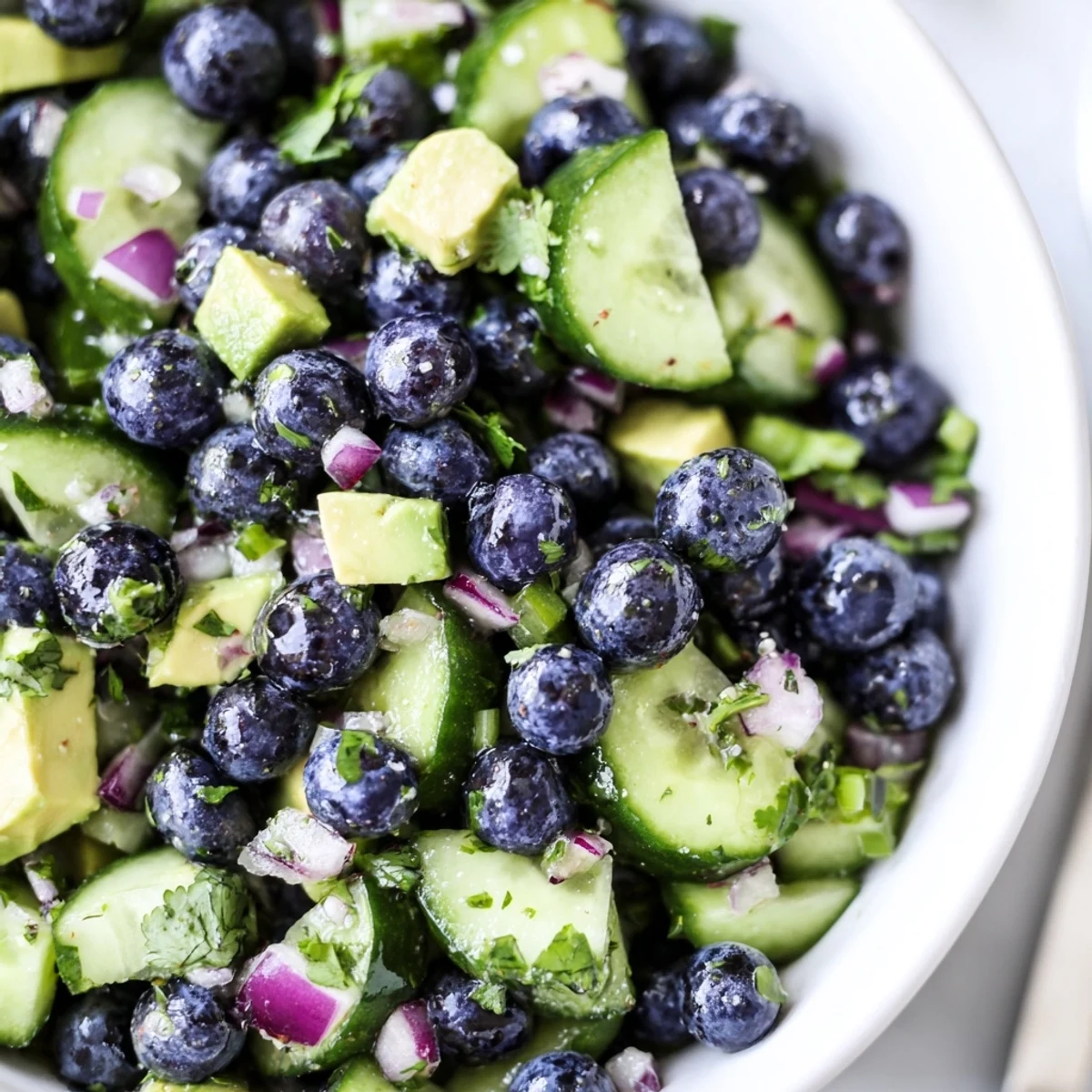 Bright blueberry cucumber salsa spooned over grilled fish on a summer plate