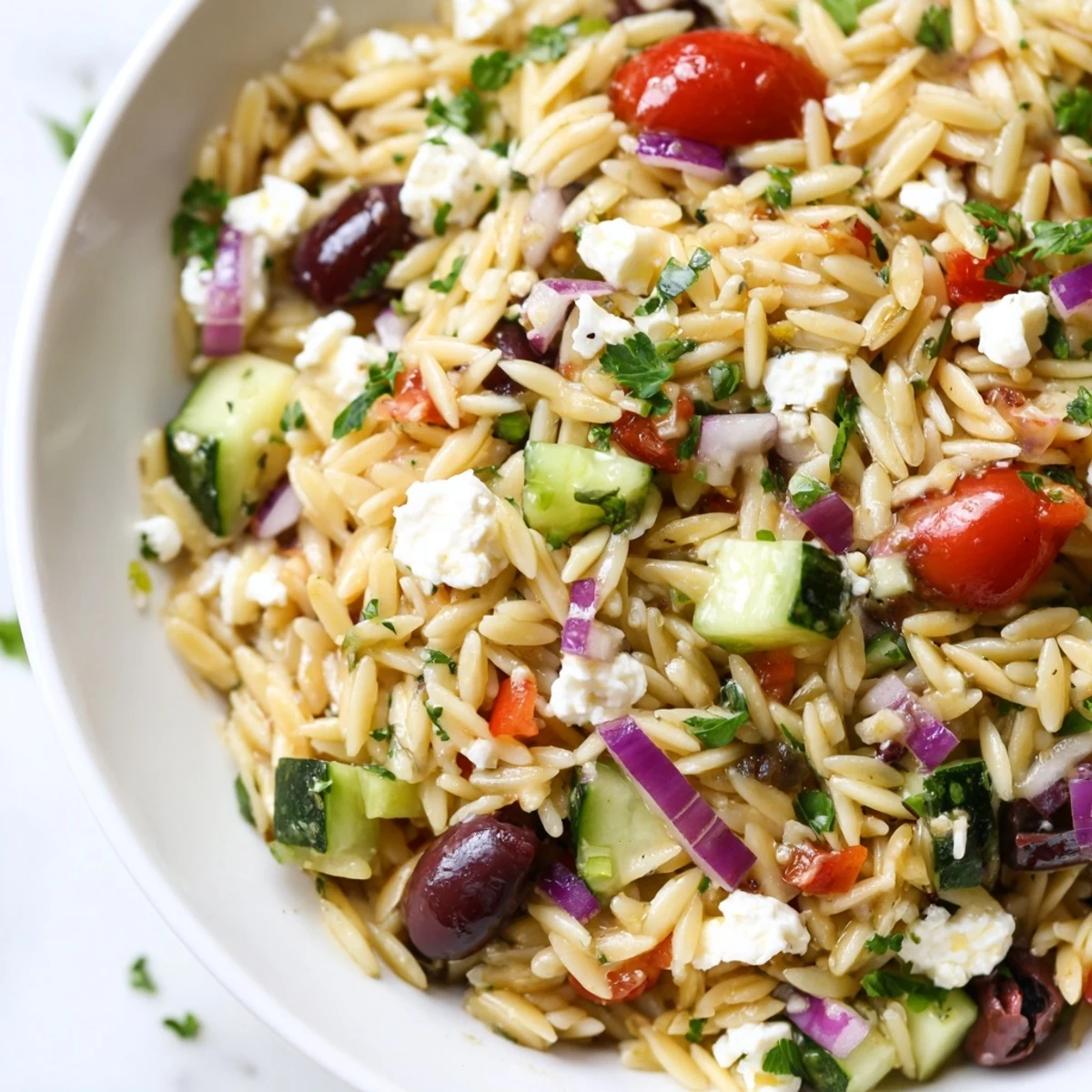 Colorful Mediterranean orzo pasta salad in a rustic bowl with tomatoes, olives, and feta cheese