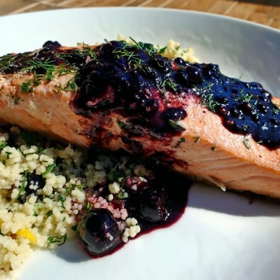Blueberry Glazed Salmon with Lemon Herb Couscous shows glossy sauce and tender fish on a vibrant dinner plate.