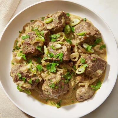 Serving of Lemongrass Coconut Braised Beef with Mushrooms over steamed rice, garnished with cilantro.