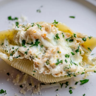 A close-up view of Creamy Seafood Stuffed Shells reveals the rich, cheesy filling of shrimp and crab inside tender pasta.  